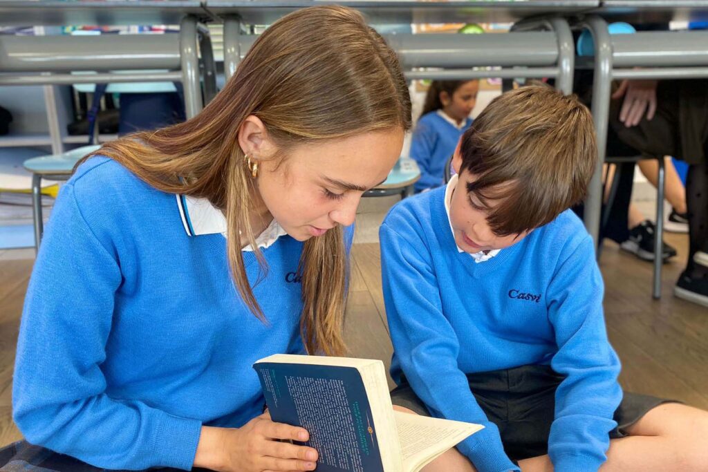 Niña leyendo un libro a un libro a un niño pequeño. Beneficios de leer