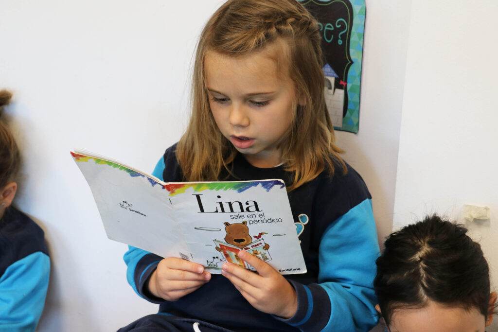 Una niña de infantil leyendo un libro por el Día del Libro