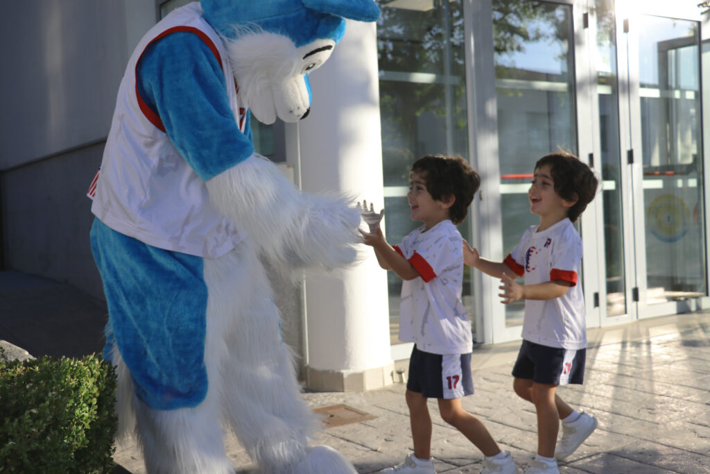 Dos alumnos abrazando a la mascota de Casvi International American School