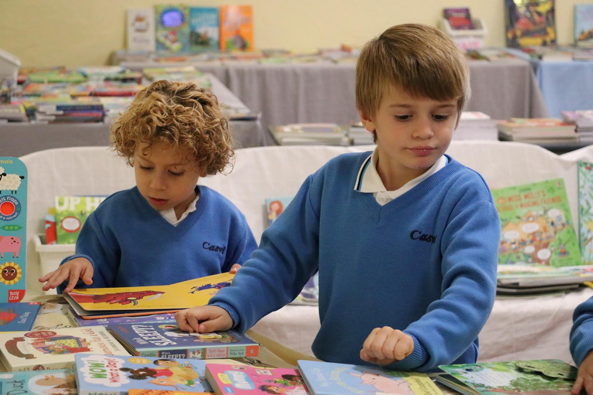 Niños escogiendo libros de lectura en el book fair para fomentar la lectura.