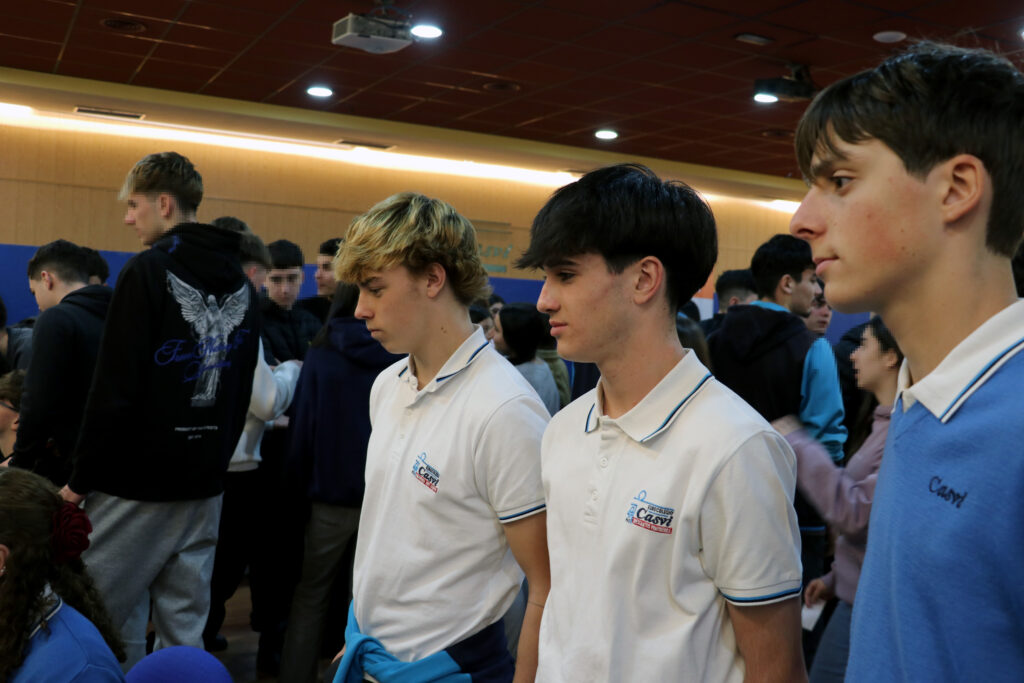 tres alumnos de uniforme miran hacia una mesa con opciones de carreras internacionales en Casvi